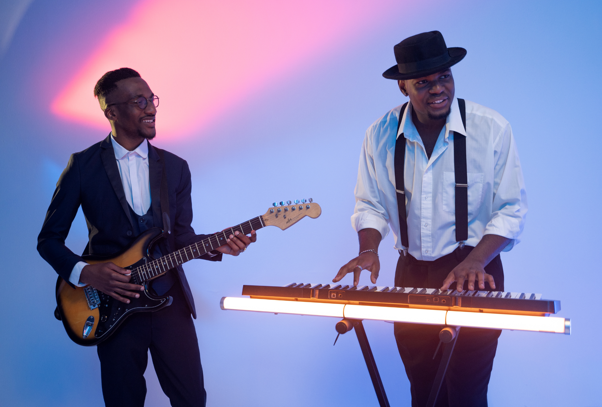 2 smiling Black gentlemen playing guitar and keyboard