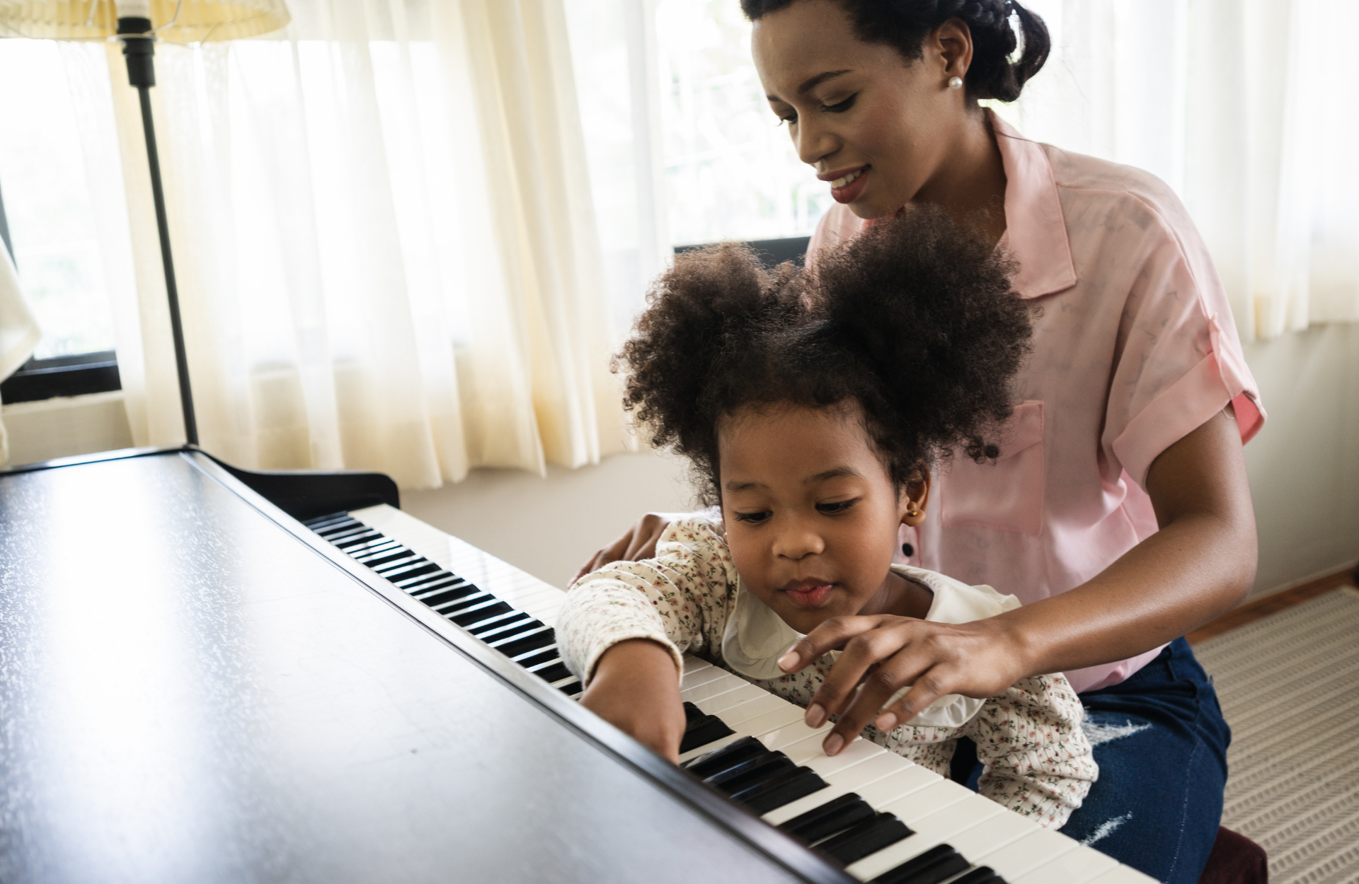 Black female teacher and black girl in front of the piano